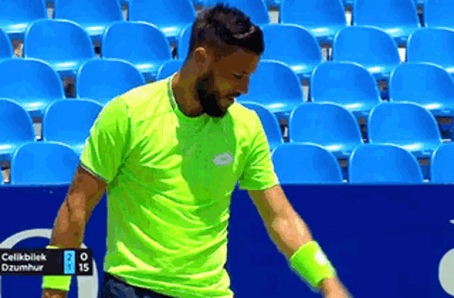 a man in a neon green shirt is playing tennis with a score of 2 to 15