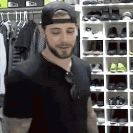 a man wearing a baseball cap is standing in front of a shoe rack .
