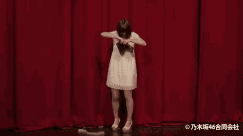a woman in a white dress stands on a stage holding a book