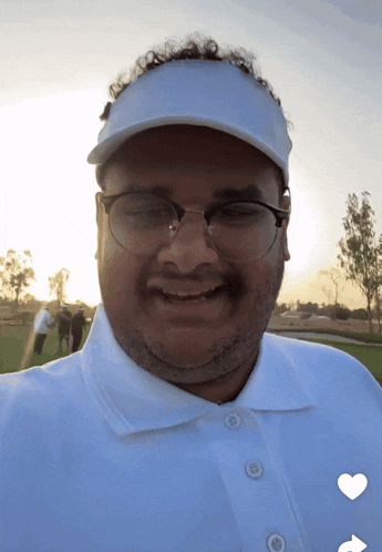 a man wearing glasses and a white hat is smiling