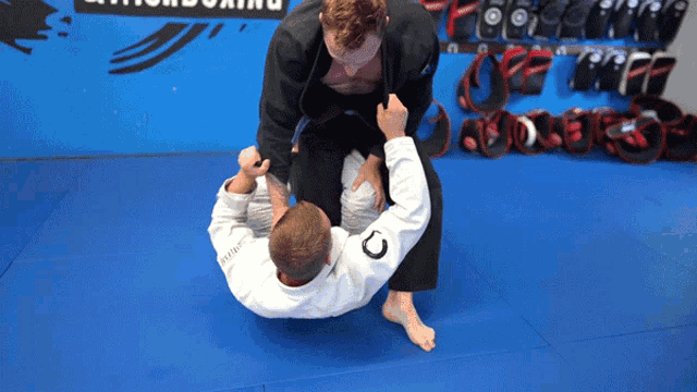 a man in a white kimono with the letter c on it is wrestling another man in a black kimono