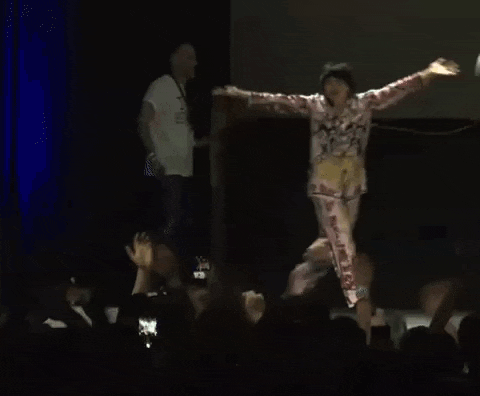 a woman is dancing on a stage in front of a crowd of people .