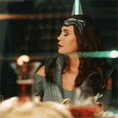 a woman wearing a party hat is sitting at a table with a martini .