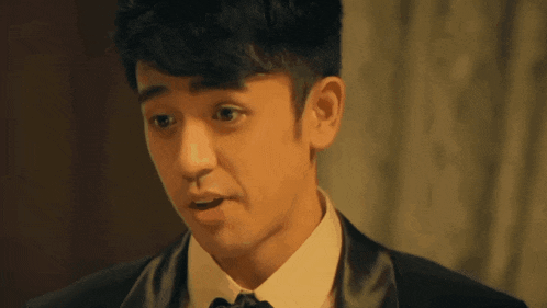 a man in a tuxedo and bow tie is making a surprised face