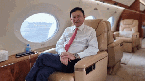 a man in a white shirt and red tie is sitting on a plane