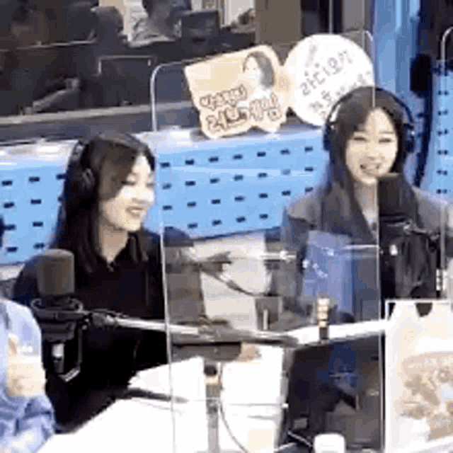 a group of women are sitting in front of a microphone in a radio station .