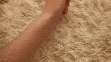 a person is filing their nails with a nail file on a fluffy carpet .