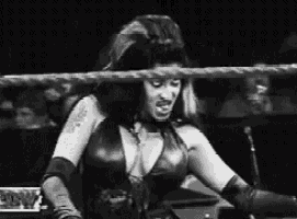 a woman is standing in a wrestling ring with a microphone .