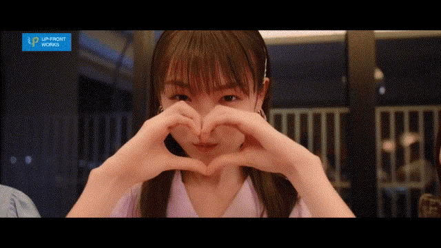 a girl making a heart shape with her hands in front of a sign that says " upfront works "