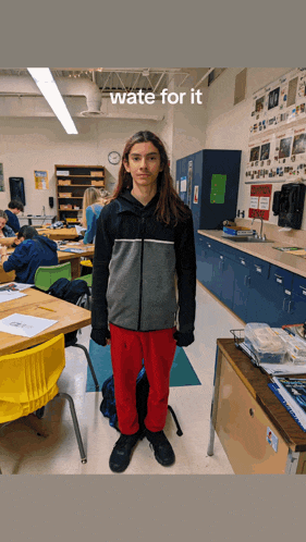 a boy with long hair is standing in a classroom with the words " wate for it " on the bottom