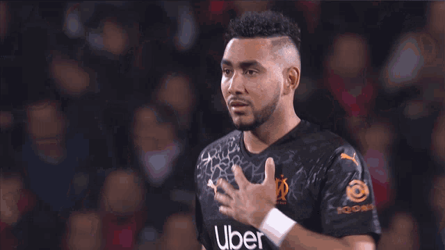 a soccer player wearing an uber jersey holds his hand to his chest