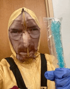 a man in a breaking bad costume is holding a stick of blue rock candy .