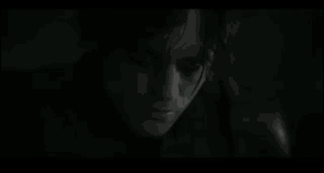 a close up of a man 's face in a dark room with his eyes closed .