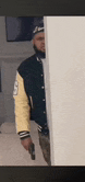 a man in a varsity jacket holding a gun