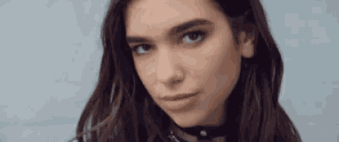 a close up of a woman 's face wearing a choker and looking at the camera .
