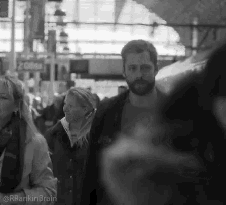 a black and white photo of people walking in a crowd