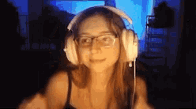 a woman wearing headphones and glasses is looking at the camera and smiling .