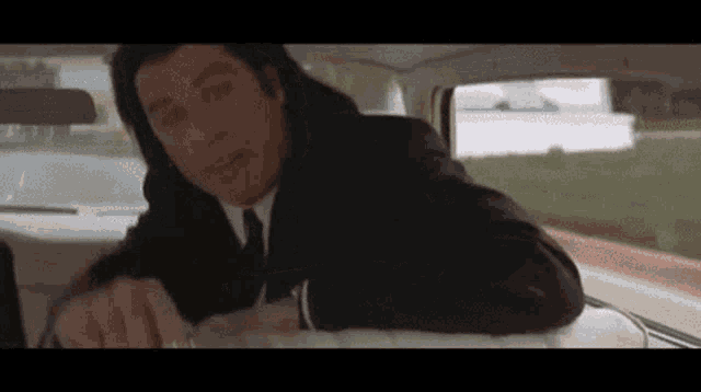 a man in a suit and tie is laying on the back seat of a car .