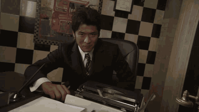 a man in a suit and tie is sitting at a desk with a typewriter