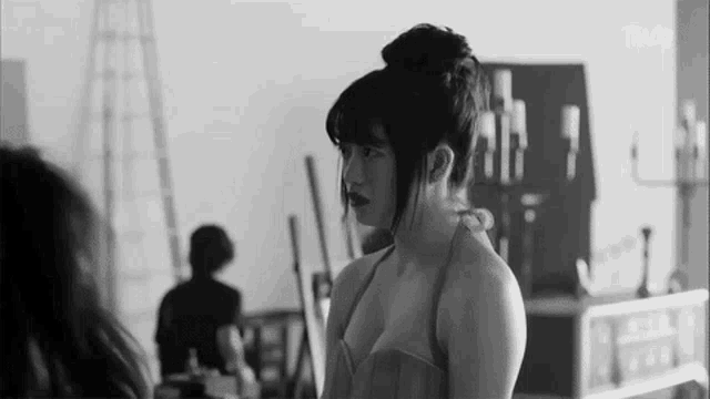 a black and white photo of a woman in a dress standing next to another woman .