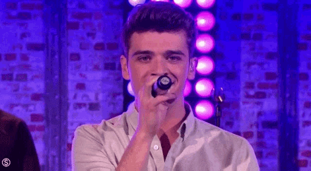 a man is singing into a microphone on a stage .
