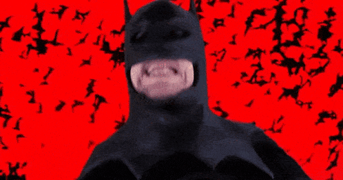 a man in a batman costume is standing in front of a pink background