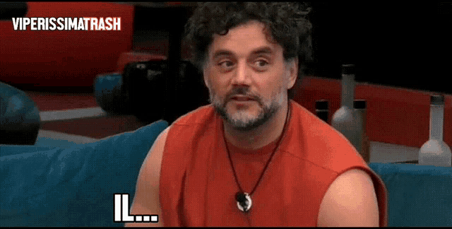 a man in a red tank top is sitting on a blue couch with the words viperissimotrash above him