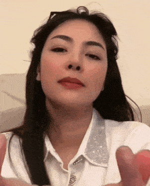 a woman in a white shirt is making a face with her hands