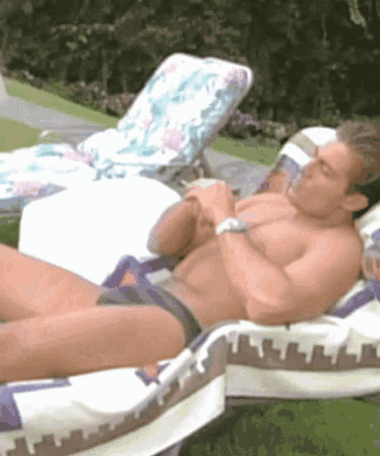 a shirtless man is laying on a lawn chair with a towel on it
