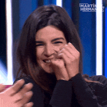 a woman is laughing in front of a martin hermano sign