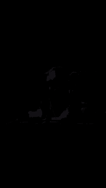 a woman is sitting at a table with her hands folded in prayer in a dark room .