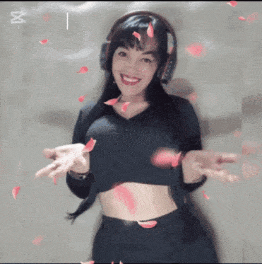 a woman wearing headphones is smiling and petals are falling from the sky
