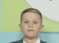 a young boy in a suit and tie is standing in front of a wall .