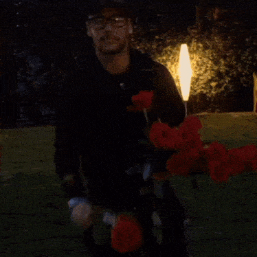 a man wearing glasses and a hat is holding a bouquet of roses .