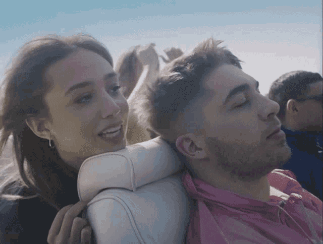 a man in a pink shirt sits next to a woman