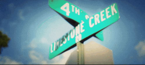 a green street sign for 4th lifestone creek against a blue sky