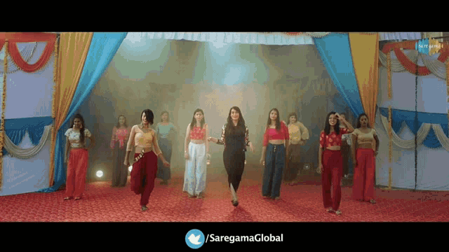 a group of women are dancing in front of a banner that says ' saregamaglobal ' on it