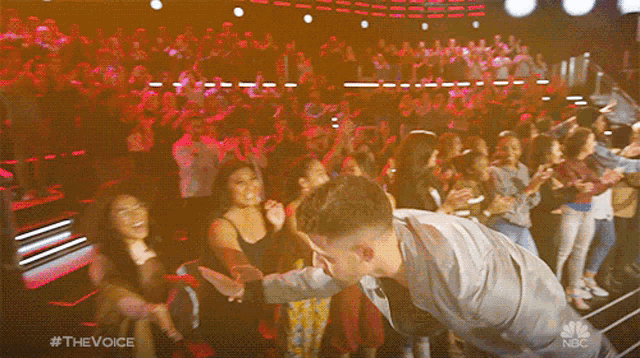 a man is dancing in front of a crowd with #thevoice on the bottom right