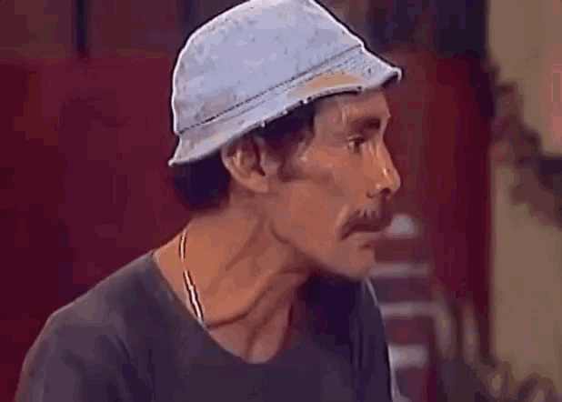 a man with a hat and a mustache is standing in front of a sign that says oi gente