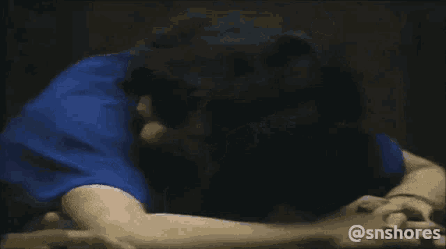a man in a blue shirt is laying down with his head on the floor .