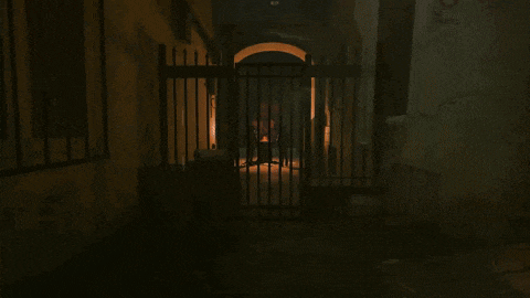 a dark alleyway with a fence and a few lights