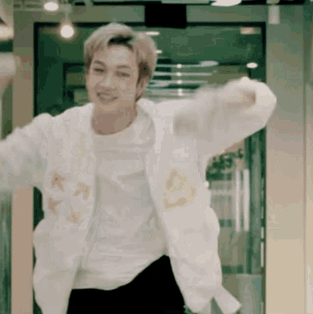 a man in a white jacket is dancing in a room .