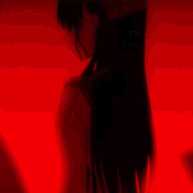 a woman in a black dress is dancing in a red light