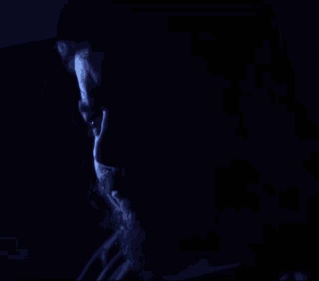 a close up of a man 's face with a beard in the dark
