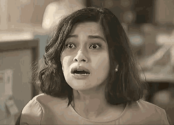 a woman is making a surprised face and looking at the camera .