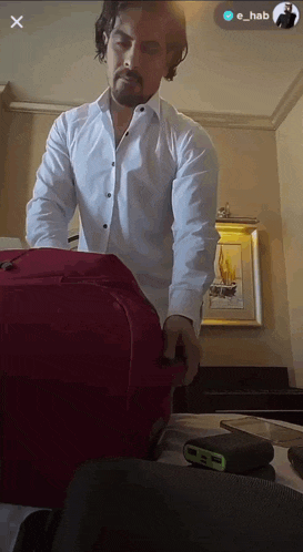a man in a white shirt is pulling a red suitcase with the name e_hab on the bottom