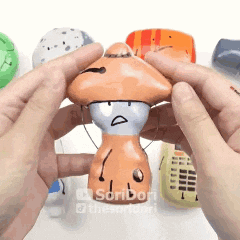 a person is holding a toy that looks like a mushroom with a sad face
