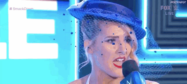 a woman wearing a blue hat is speaking into a microphone .