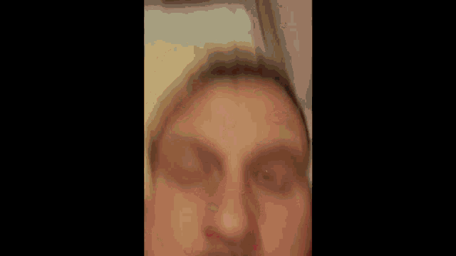 a man with a beard is making a funny face while laying on a bed .