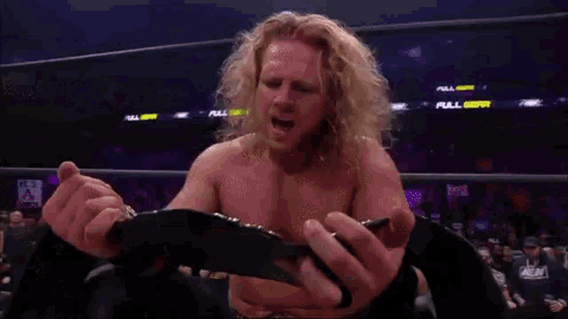 a wrestler is hugging another wrestler in a wrestling ring during a match .